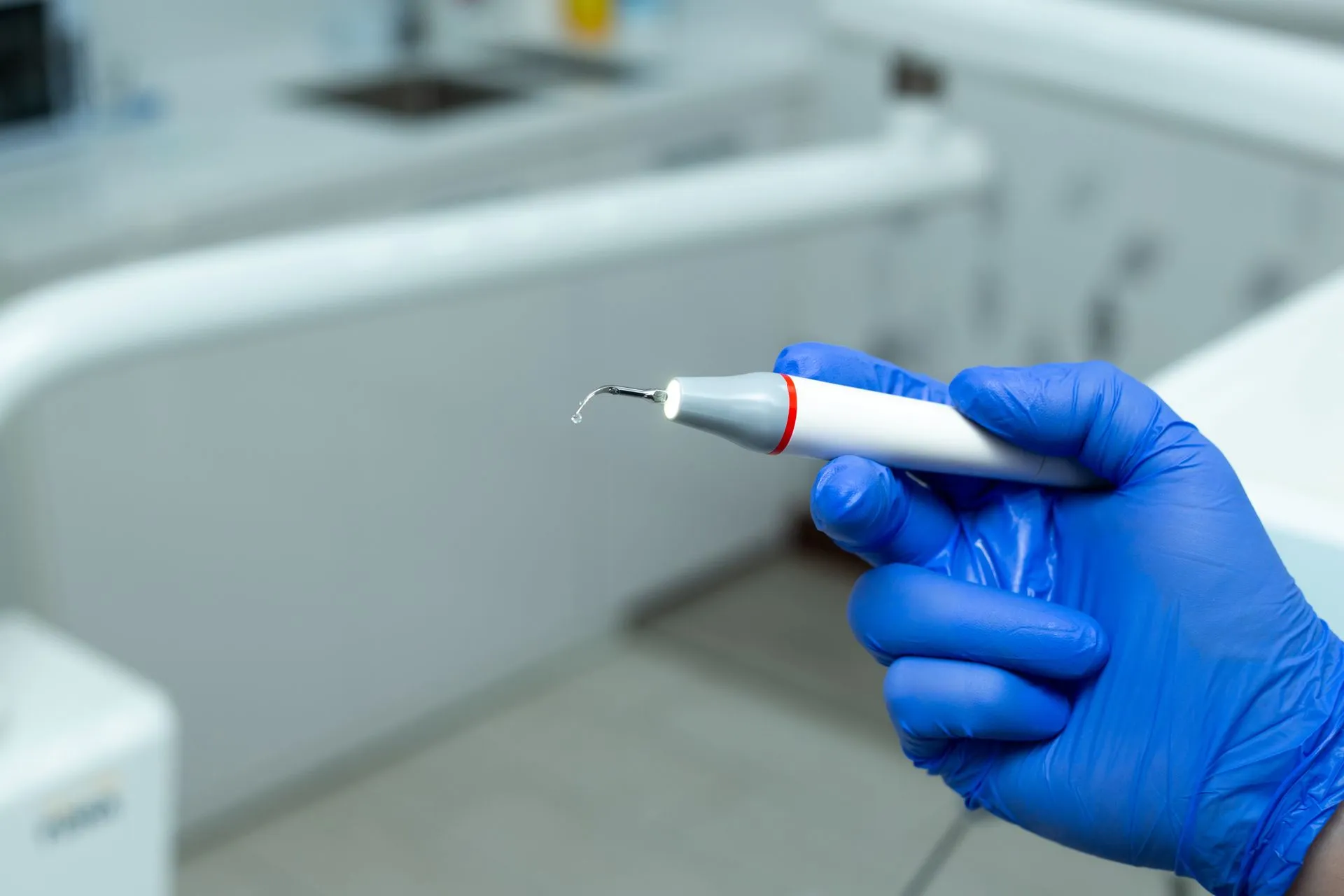 Instrumento de limpieza dental sujeto por un profesional con guantes en Clínica Dental Vigoar