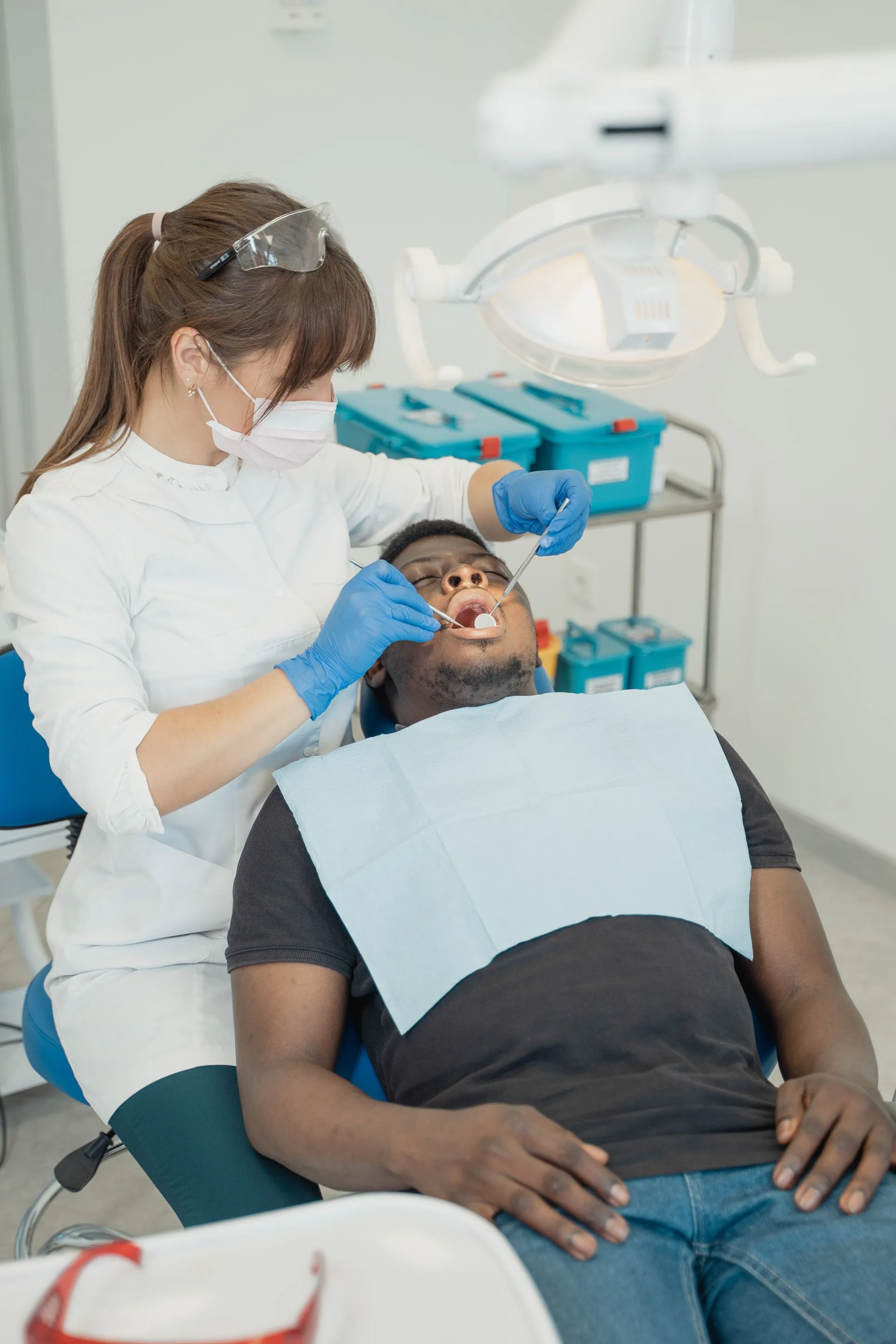 Odontóloga revisando la boca de un paciente en el gabinete de Clínica Dental Vigoar